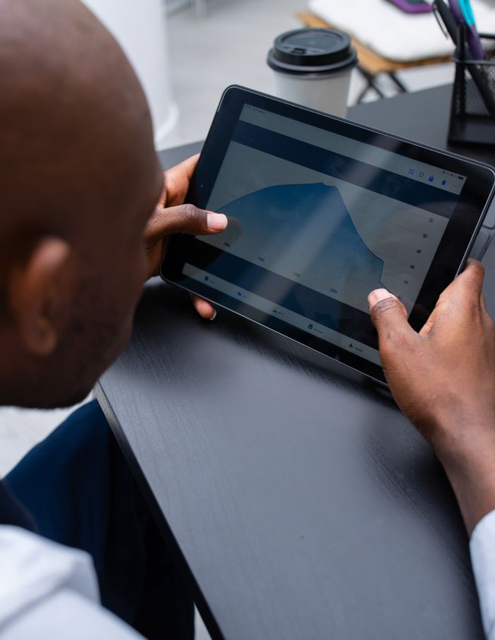 services-09 Man viewing graph on tablet at modern workspace, close up.